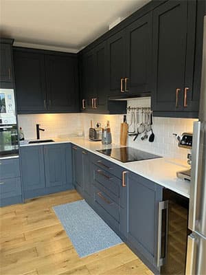 Fitted kitchen with dark shaker-style cabinetry and copper handles