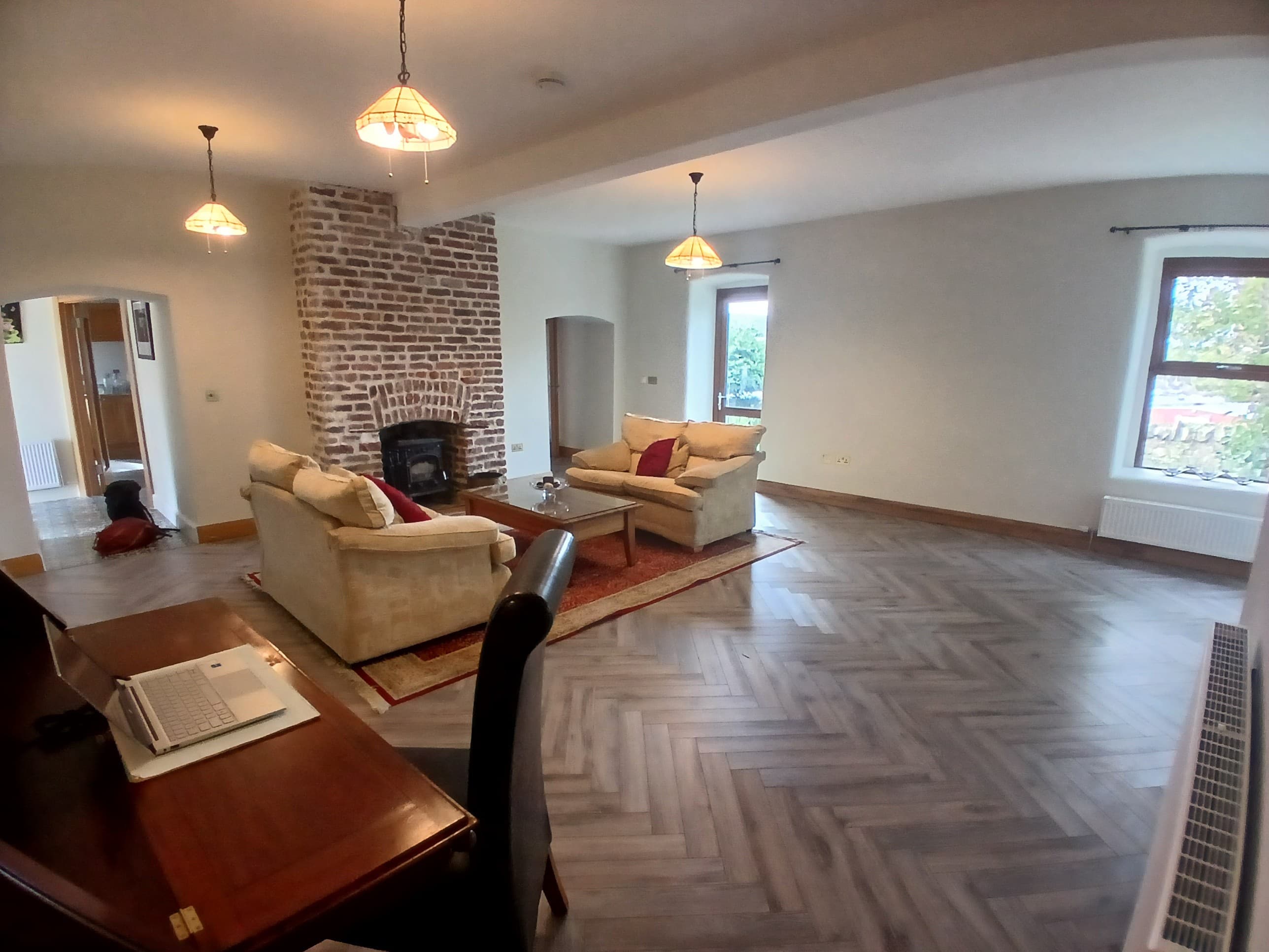 Living room with inglenook brick fireplace and herringbone parquet flooring