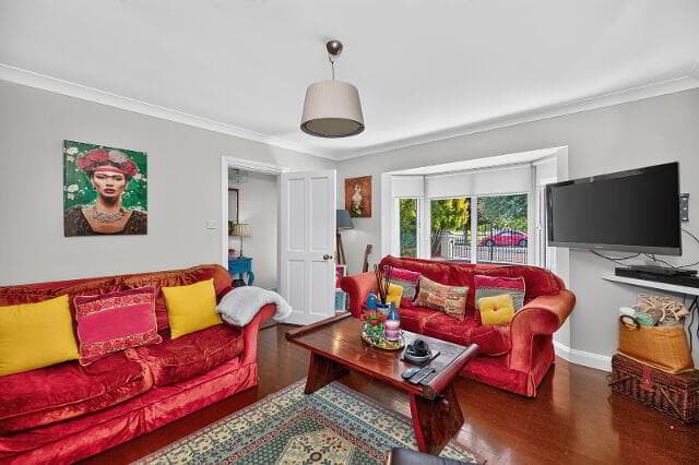 Second reception room with red sofas and bay window overlooking the front