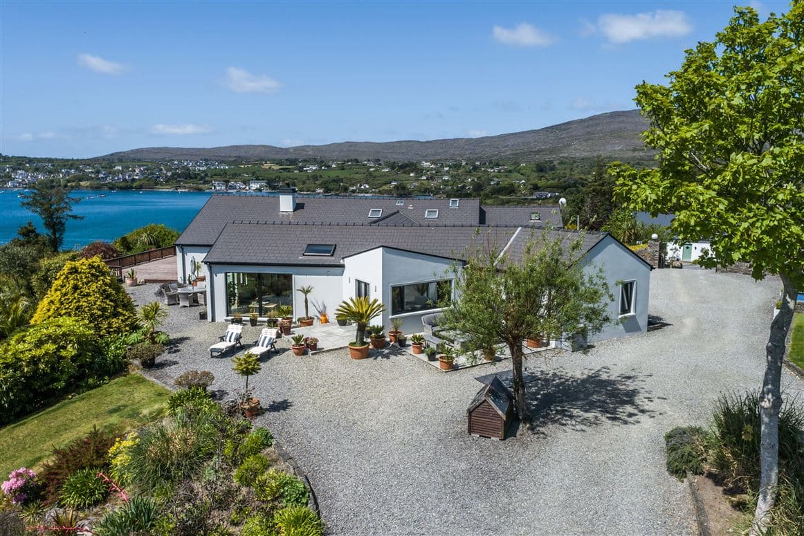 Aerial view of the rear terrace, sun loungers and gardens with hills beyond
