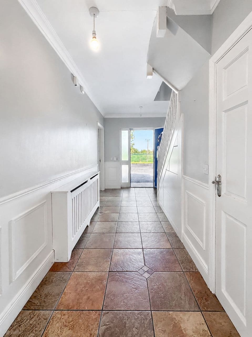 Hallway view toward the front door with under-stairs storage